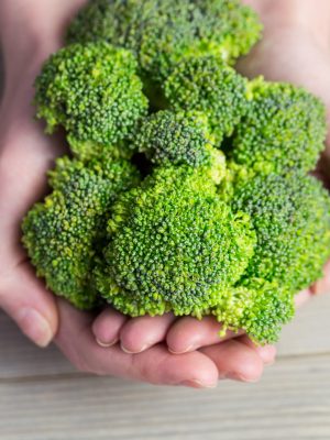 Woman showing fresh green brocolli in close up